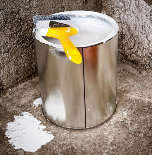 can-of-white-paint-and-yellow-brush-on-concrete-floor