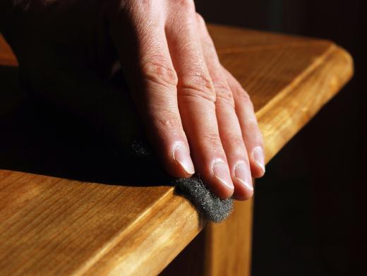 hand-with-cloth-applying-finish-to-wood-furniture