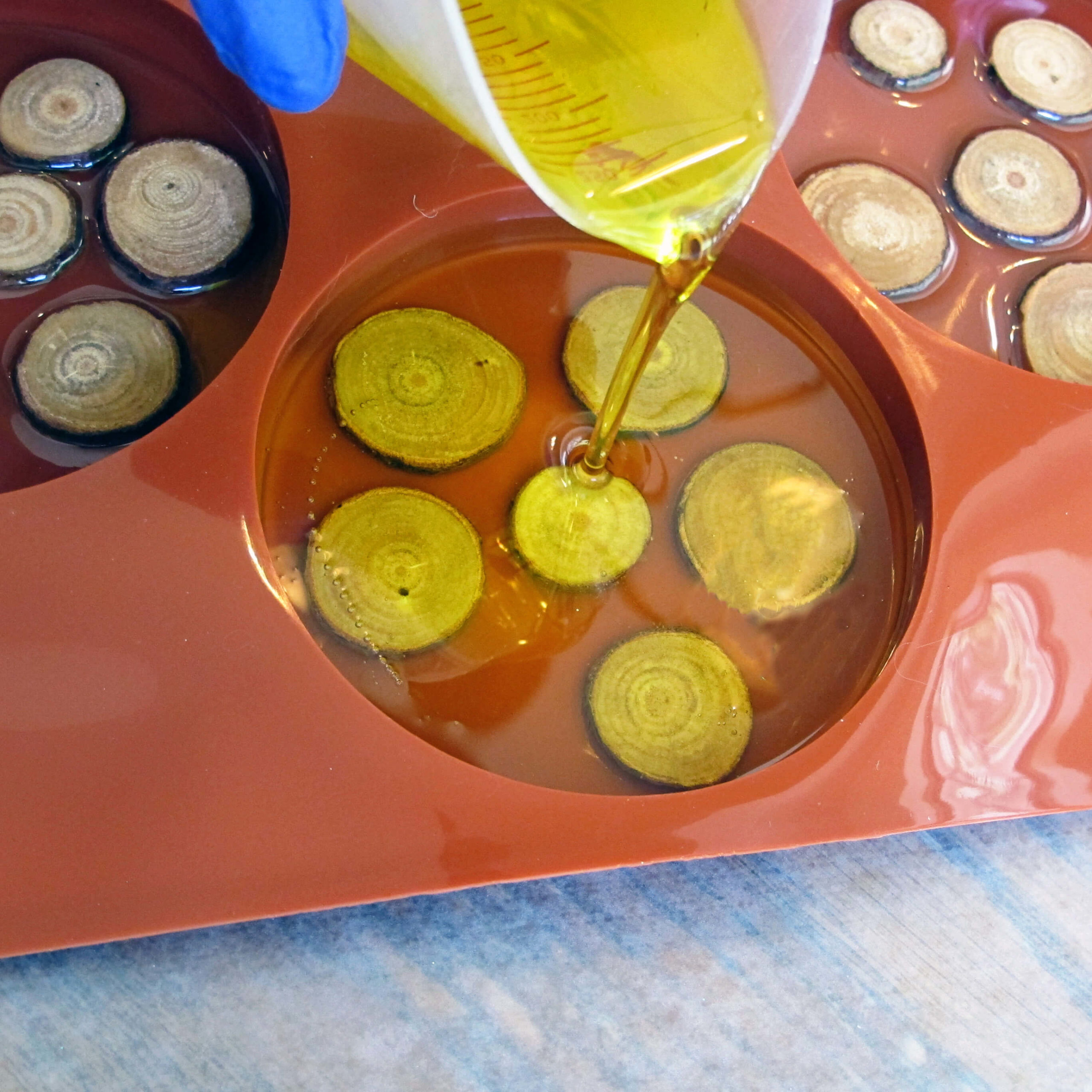 pouring-yellow-resin-into-a-silicone-coaster-mold-scaled-1